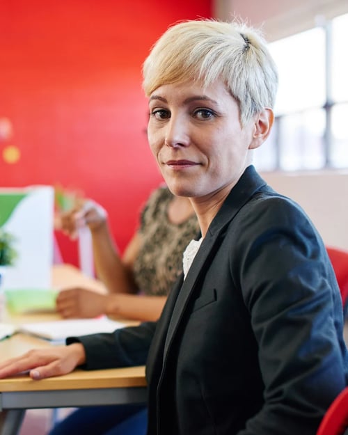 Confident female designer sitting at her desk for a brainstorming in red creative office space
